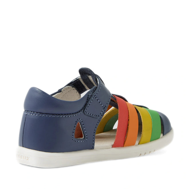 The Bobux IWalk Tidal Sandal Multi Vintage Indigo Closed Toe Toddlers features a navy blue heel and vibrant straps in red, orange, yellow, and green. With a closed-toe design, open side cutout, and white sole, these stylish sandals are both comfortable and practical for little feet. Made from water-friendly leather, they’re ideal for playtime indoors or outdoors., 9420074807854, 9420074807861, 9420074807878, 9420074807885, 9420074807892