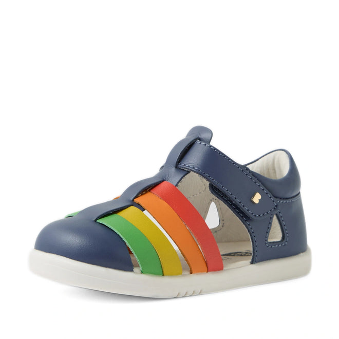 The Bobux IWalk Tidal Sandal Multi Vintage Indigo Closed Toe for toddlers features a water-friendly leather design in blue with a white sole and colorful rainbow straps—green, yellow, orange, and red—on the side, making it ideal for little adventurers., 9420074807854, 9420074807861, 9420074807878, 9420074807885, 9420074807892
