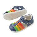 A pair of Bobux IWalk Tidal Sandal Multi Vintage Indigo Closed Toe Toddlers, featuring vintage indigo blue with white soles and multicolored straps in green, yellow, orange, and red across the top. Crafted from water-friendly leather, these closed-toe toddler sandals are perfect for active little ones on summer adventures., 9420074807854, 9420074807861, 9420074807878, 9420074807885, 9420074807892