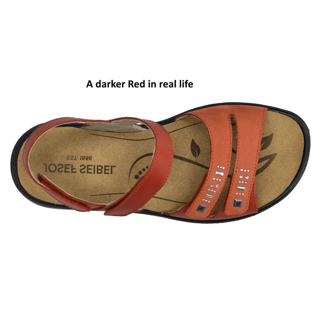 Top view of the Josef Seibel Ibiza 86 Womens Leather Comfort Sandal in Rot Red, showcasing two front straps adorned with silver studs and an ankle strap, all set on a tan footbed. Text above reads, A darker Red in real life., 53187, 4062838863208, 4062838863215, 4062838863222, 53191, 53192