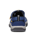 Rear view of the Keen Kids Newport H2 sandal in Blue Naval Academy Yellow, featuring a durable blue and black upper, a gray textured non-marking sole for added grip, a reflective strip along the heel, and a yellow Keen logo tag on the left side. Available in US sizes 8 toddlers to 6 youths.
