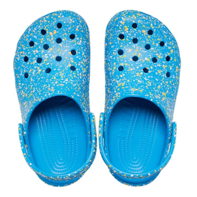 The Crocs Kids - Toddlers Classic Clog K Paint Splatter Print Blue Pink Multi features lightweight blue clogs for kids with colorful paint splatters, ventilation holes, and adjustable heel straps, shown from above on a white background., 47582, 198445214134, 198445214141, 198445214158, 198445214097