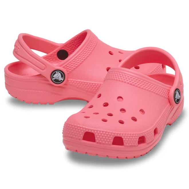 A pair of Crocs Kids Youths - Classic Clog K in Guava Pink with ventilation holes and adjustable heel straps is shown on a white background.