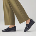 A person stands on a light gray floor wearing olive green pants and Pitillos Womens Lycra and Patent Leather Shoe 10731, featuring a black wedge heel, subtle textured pattern, and removable innersole, against a plain background., 8445191655554, 8445191655561, 8445191655578, 8445191655585, 51923, 51924