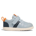 The Pretty Brave SID Leather Trainer First Walker in indigo blue and grey features a cream sole, navy details, white laces, hook-and-loop strap, and orange heel accents—podiatrist approved shoes ideal for growing toddlers.