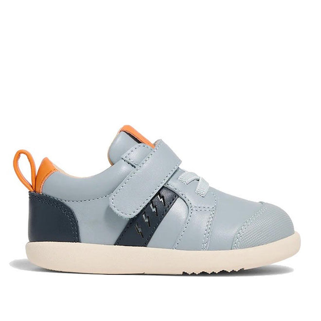 The Pretty Brave SID Leather Trainer First Walker in indigo blue and grey features a cream sole, navy details, white laces, hook-and-loop strap, and orange heel accents—podiatrist approved shoes ideal for growing toddlers.
