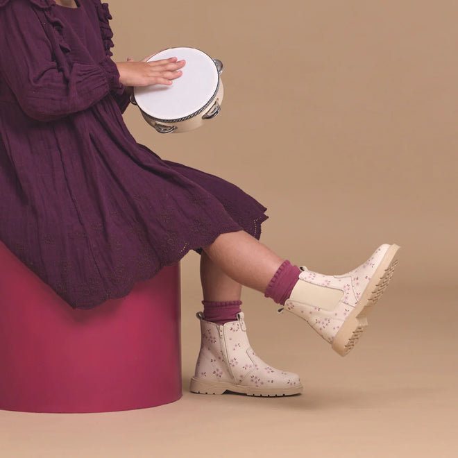 A child in a purple dress and Pretty Brave Girls Hudson Winter Bloom Pink Leather Boots sits on a magenta stool, holding a tambourine against a beige background., 9420075363205, 9420075363199, 9420075363182, 9420075363175, 9420075363168, 9420075363151, 9420075363144, 9420075363137, 9420075363120, 9420075363113