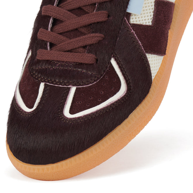 Close-up of the Rollie Womens Pace Dark Cherry Bone Suede Sneaker's toe box, showcasing dark cherry suede, pony hair, white trim, light blue accent panel, mesh side panel, and a translucent gum outsole in a minimalist style., 9339554000315, 9339554000317, 9339554000164, 9339554000056, 9339554000182