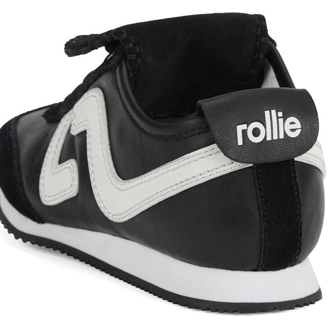 A close-up of the Rollie Womens Shift Black/Bone Sneaker, showing the back and side with a white zigzag design, black heel tab displaying "rollie" in white lettering, and a white sole with a black bottom., 9339554369945, 9339554362427, 9339554100234, 9339554006246, 9339554000138