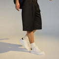Person in a wlaking poise wearing a black skirt, white rollie club court lace up sneakers, and socks on a neutral background.,
9781760790097,
9781760790103,
9781760790110,
9781760790127,
9781760790134,
9781760790141,