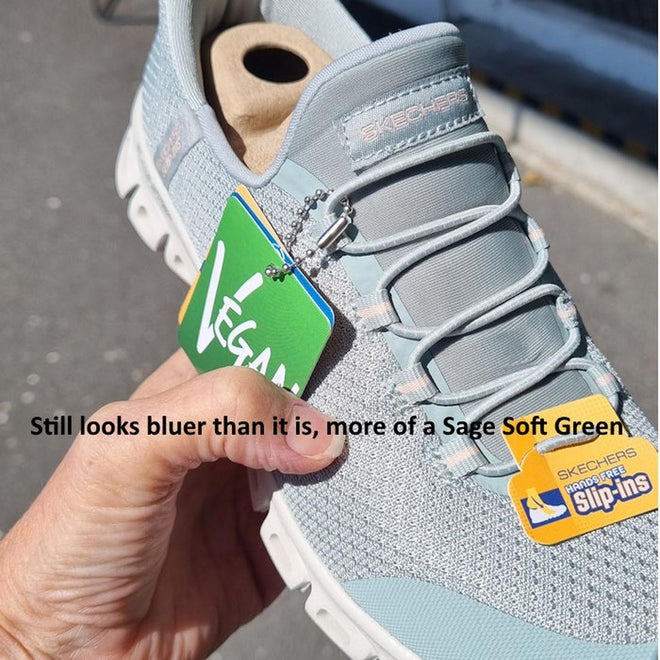 A hand holds a Skechers Womens Slip-Ins Glide Step Pursuit Sage sneaker labeled Vegan in sunlight. The shoe, with Air-Cooled Memory Foam, appears light blue but is called Sage Soft Green. Text overlays near the sneaker., 199025100960, 199025100984, 48989, 199025101004, 48991, 199025101028, 48993, 199025101042, 199025101059