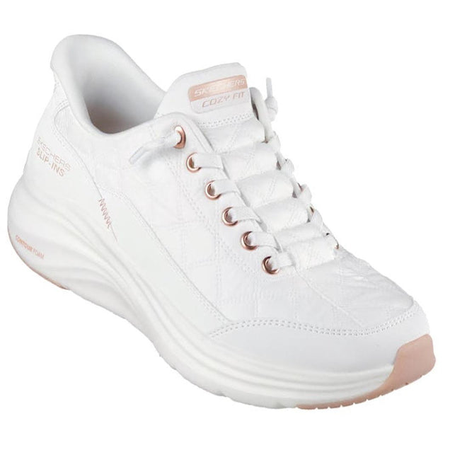 The Skechers Womens Slip In Contour Foam Golden Hour Cozy Fit in white and rose gold features blush pink accents, quilted pattern, Air-Cooled Memory Foam comfort, and "Skechers Hands Free Slip-ins" branding.