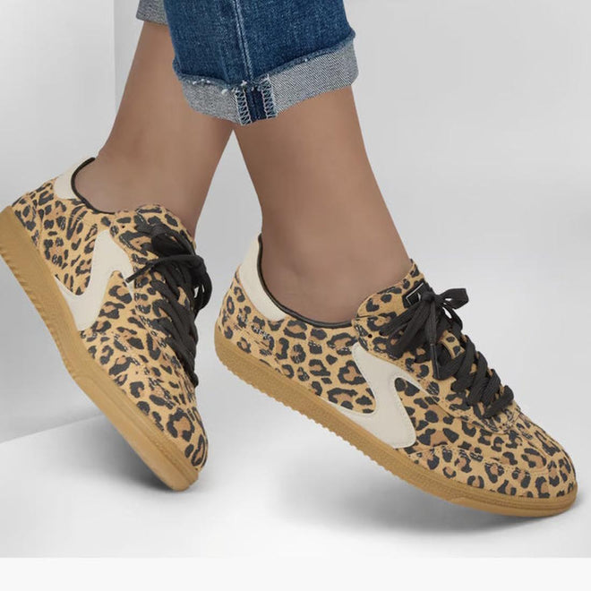 A person in rolled-up blue jeans and Skechers Womens HotShot On The Prowl Leopard Suede Sneakers with beige soles, black laces, and Air-Cooled Memory Foam stands against a plain light background., 52252, 199025014359, 199025014373, 199025014380, 199025014397, 199025014410, 52257