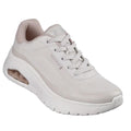 The Skechers Womens Uno Flex Spring On Air Taupe Trainer is a light beige sneaker with a thick white sole, visible air-cushioned heel, mesh upper, laces, subtle side and tongue branding, and a comfortable Memory Foam insole.