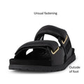 The Woden Lisa Women's Leather 2 Strap Sandal in black is shown from the front, featuring a unique fastening design, chunky buckle straps, and gold hardware. Text labels point out the distinctive fastening and outside of the foot., 5713326518276, 5713326518283, 5713326518290, 5713326518306, 5713326518313, 3935713326518320, 5713326518269