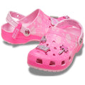 A pair of pink women's Barbie branded clogs with decorative elements charms on a white background