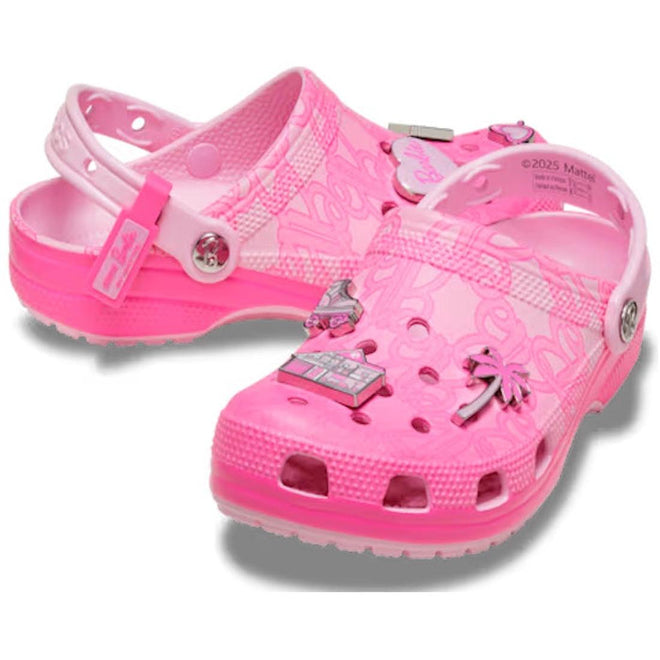 A pair of pink women's Barbie branded clogs with decorative elements charms on a white background
