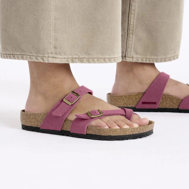 A womens lower legs and feet weraing a pair of birkenstock mayari cross over sandals with toe prong in berry. 4066648519324,
4066648519362,
4066648519409,
4066648519447,