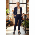 A confident older woman in a navy suit and Ziera Solar XW Women's Casual Sneaker Zip Ink Blue Leather stands in a stylish café, hands in pockets. Sunlight streams through large windows as people chat, enhancing the modern, relaxed atmosphere around her., 9355342543731, 9355342095476, 9355342095483, 9355342095490, 9355342095506, 9355342095513, 51004