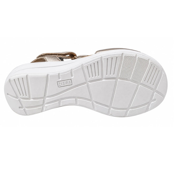 The image displays the white grooved sole of the Ziera Nazly2 Platino Gold White XW Womens Leather Sandal, viewed from underneath to highlight its tread pattern and the embossed Ziera branding at the center. This distinctive sole design offers excellent traction and features high arch support, enhancing overall comfort for the wearer.