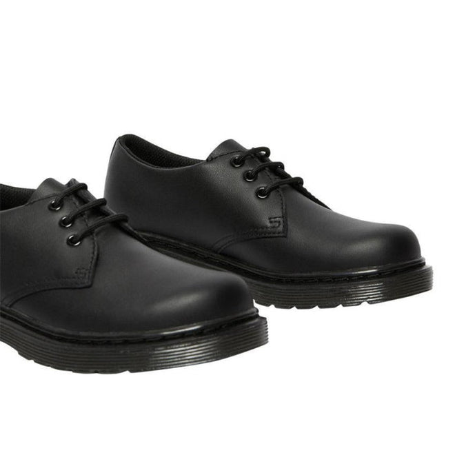A pair of Dr Martens kids 1461 Mono J Lace Up School Shoes in black, featuring smooth leather and thick rubber soles, displayed from a slightly angled side view on a white background., 20644, 20645, 190665364316, 190665364217, 20648, 190665364231, 20650, 190665364255