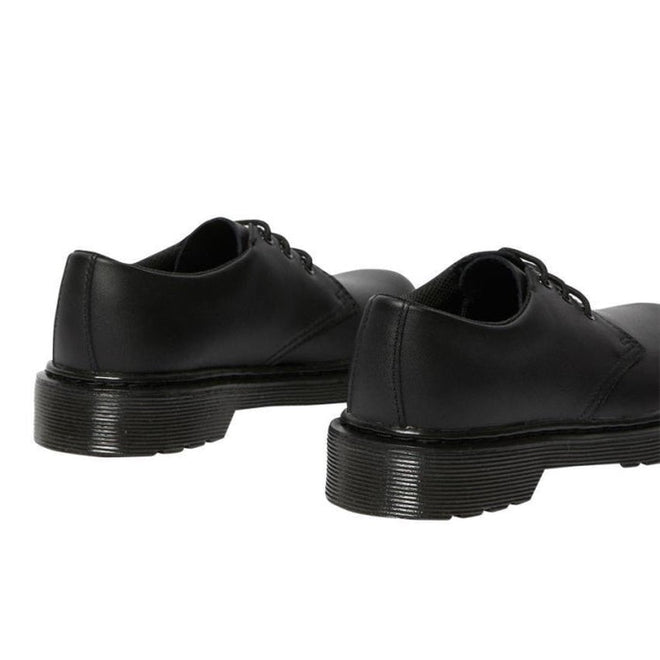 A pair of Dr. Martens kids 1461 Mono J black lace-up school shoes is shown from the back on a white background, featuring their thick, grooved soles and smooth leather finish., 20644, 20645, 190665364316, 190665364217, 20648, 190665364231, 20650, 190665364255