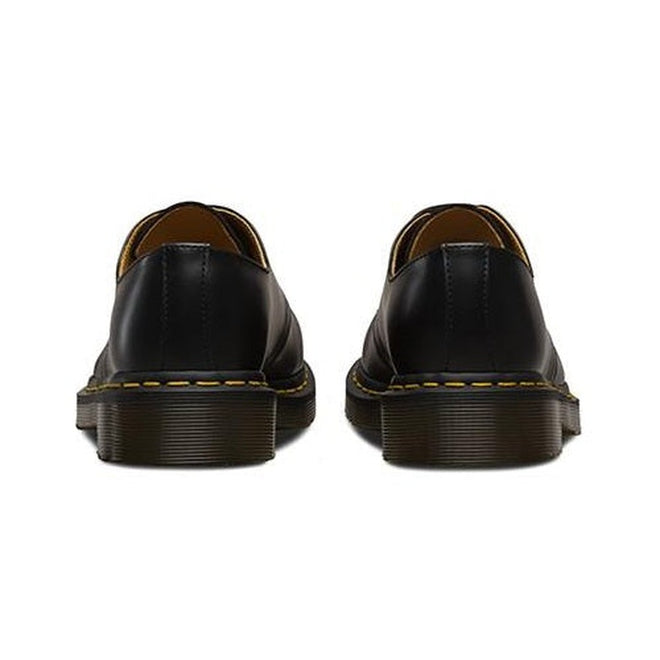 rear heel view of a apair of Dr Martens 1461 in black leather showing stitching detail on heel and yellow stitching around sole.,
800090826883,
800090826906,
800090826920,
800090797534,
800090797558,
800090826975,
800090797565,
800090797572,
800090797596,
800090797602,
800090797626,