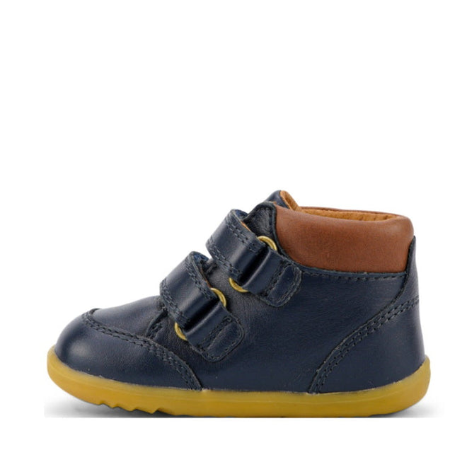 The Bobux Iwalk Timber Navy Leather Boot 632619 is a small dark blue premium full grain leather toddler shoe with two adjustable straps, brown padded ankle collar, yellow stitching, and yellow rubber sole, shown from the side on a white background., 9420068529298, 9420068529304, 9420068529311, 9420068529328, 9420068529335