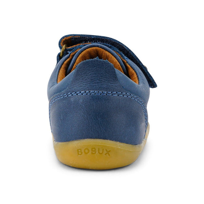 A close-up rear view of the Bobux Step Up Port Shoe Midnight Blue727718, a unisex children's shoe with a leather upper and beige sole, featuring "BOBUX" embossed on the heel, photographed on a white background., 9420068525566, 9420068525573, 9420068525559