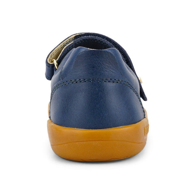 A close-up rear view of the Bobux Kid+ Delight Mary Jane Navy 831615Z girls’ leather shoe with a tan rubber sole and Velcro strap, styled in classic Mary Jane fashion, shown against a white background., 9420075721210, 9420075721227, 9420075721234, 9420075721241, 9420075721258, 9420068516847, 9420068516854