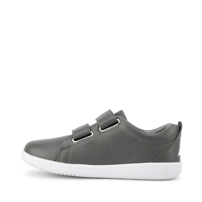 The Bobux Kids + Plus Grass Court Smoke Grey Velcro Trainers 832446 are gray kids' street shoes with two Velcro straps and a white rubber sole, shown from the side on a plain white background., 9420068518025, 9420068518032, 9420068518049, 9420068518056, 9420068518063, 9420068518070, 9420068518087