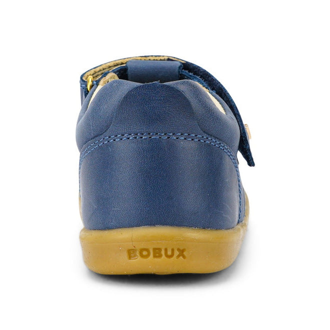 The Bobux IW Iwalk Louise Midnight Blue 633030 is a children's T Bar shoe with a blue leather upper and tan rubber sole, viewed from the back. The BOBUX name is embossed on the heel of the sole., 9420068521841, 9420068521858, 9420068521865, 9420068521872, 9420068521889