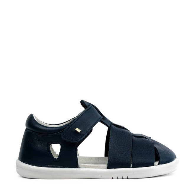 The Bobux IWalk Tidal Closed Toe Quick Dry Sandal Navy 634404A is a children's navy blue sandal with a closed toe and heel, adjustable Velcro strap, cut-out details, quick dry leather, and a white rubber sole, shown on a white background., 9420062048221, 9420062048238, 9420062048245, 9420062048252, 9420062048269