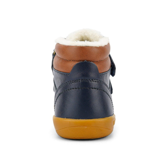 The Bobux Kid+ Timber Arctic WATERPROOF Boot Navy 836003E is shown from the back, featuring navy blue leather, a brown collar, white fuzzy lining, and a tan rubber sole against a white background., 9420068529489, 9420068529496, 9420068529502, 9420068529519, 9420068529526, 9420068529533, 9420068529540