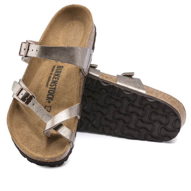 a pair of Birkenstock Mayari Metallic Graceful Taupe Regular Width- thin strappy sandals with bubkle adjustment over the foot and on the outside of the foot near the toe area. Straps cross cross over the toes and a separate strap over the top of the foot. Suede foot bed with arch support. Mostly a women's styel