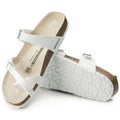 a pair of Birkenstock Mayari Womens Birko Flor White Regular Width- thin strappy sandals with bubkle adjustment over the foot and on the outside of the foot near the toe area. Straps cross cross over the toes and a separate strap over the top of the foot. Suede foot bed with arch support. Mostly a women's styel