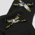 Close-up of Dr Martens Ankle Bow Cotton Blend Socks in black, featuring small black satin bows with yellow AirWair branding, ribbed texture, and overlapping display on a light background., 190665563641, 190665563634