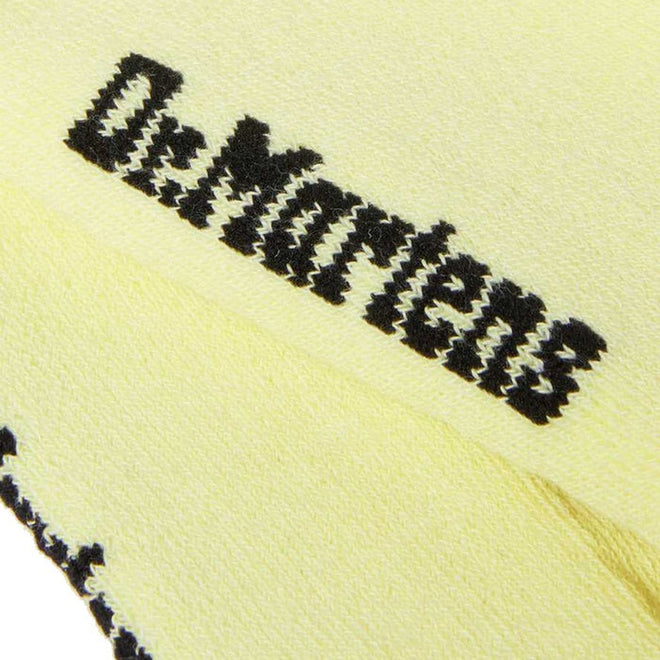 A close-up of Dr Martens Ankle Bow Cotton Blend Socks in lemon shows the soft yellow fabric, bold black embroidered "Dr. Martens" text, and stylish, machine washable design., 190665558562, 190665558555