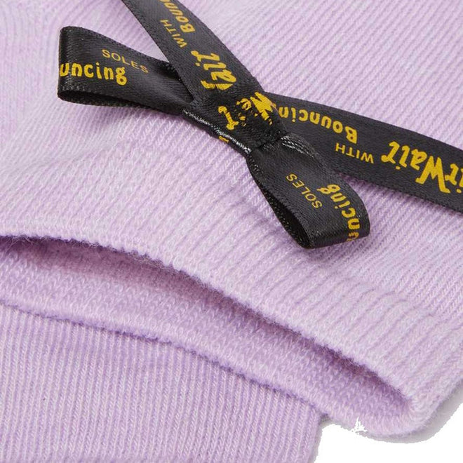 A close-up of Dr Martens Ankle Bow Cotton Blend Socks in lilac, folded and tied with a black ribbon, featuring yellow “with bouncing soles” text. Available in Small/Medium (up to UK7) and Medium/Large (above UK7)., 190665558609, 190665558593