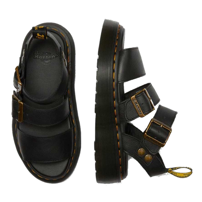 A flaylay shot of the Dr Martens Quad Gryphon Sandal in Black in Pisa Leather. A top down view of the inner sole footbed of the right foot. A side outer foot view of the left foot showing yellow stitching around the sole. 2 staps over yhe top of the foot. The higher with buckle adjustment ans the adjustable strap around the leg.,
190665318654,
190665318661,
190665318678,
190665318685,
190665318692,
190665318708,
190665318715,
