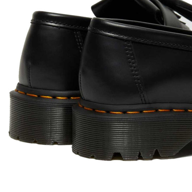 Close-up of the back and heels of two Dr Martens Adrian Bex Black Smooth Platform Loafer Shoes, featuring thick grooved soles and signature yellow stitching on the base., 183681, 190665420241, 190665420166, 190665420173, 190665420180, 190665420197, 190665420203, 190665420210, 190665420227
