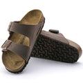 a pair of Birkenstock Arizona Birko Flor Mocca Regular Width with double straps, one over the foot and one over the toes with buckle adjustment. Staps are linked at the sides of the foot. Synthetic straps and a suede leather footbed,