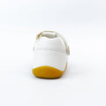 A Bobux Step Ups Cross Jump White 731106 closed toe sandal for first walkers, shown from the back on a white background. It features a white leather upper, yellow sole, and BOBUX embossed on the heel., 9420062083901, 9420062083918, 9420062083925, 9420062083932