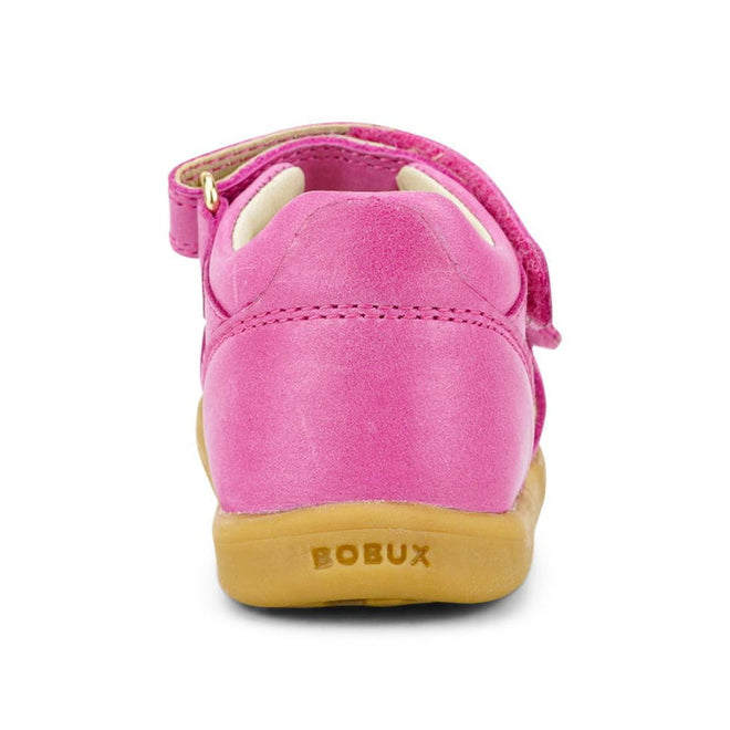 A close-up rear view of the Bobux iwalk IW Magic Girls Leather Sparkle Sandal in bright pink, featuring a tan rubber sole with stitching, a strap, and embossed BOBUX branding—ideal first-walker shoes., 9420068522749, 9420068522756, 9420068522763, 9420068522770, 9420068522787