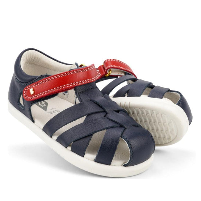 The Bobux Iwalk IW Tropicana II Sandal 638309 features a navy color with a red strap, white soles, closed toe design, side openings for ventilation, and quick-dry leather for kids’ all-day comfort.