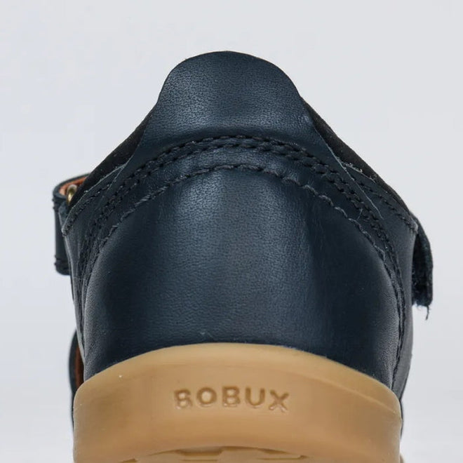 Close-up of the back of the Bobux Kid+ Plus Roam Navy Closed Toe Sandal 830503A with visible stitching, tan rubber sole, and BOBUX embossed on the heel—an ideal choice for boys' closed toe sandals., 9420062049884, 9420062049891, 9420062049907, 9420062049914, 9420062049921, 9420062049938, 9420062049945