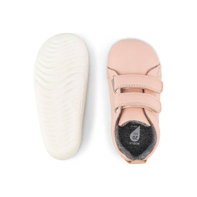The Bobux Step Up SU Grass Court Trainer 728909J in Seashell Pink is a pair of toddler leather sneakers with white soles, two adjustable hook-and-loop straps, and a soft, flexible design for first walkers. Shown from top and bottom views., 9420075792913, 9420075792333, 9420075789821, 9420075791978