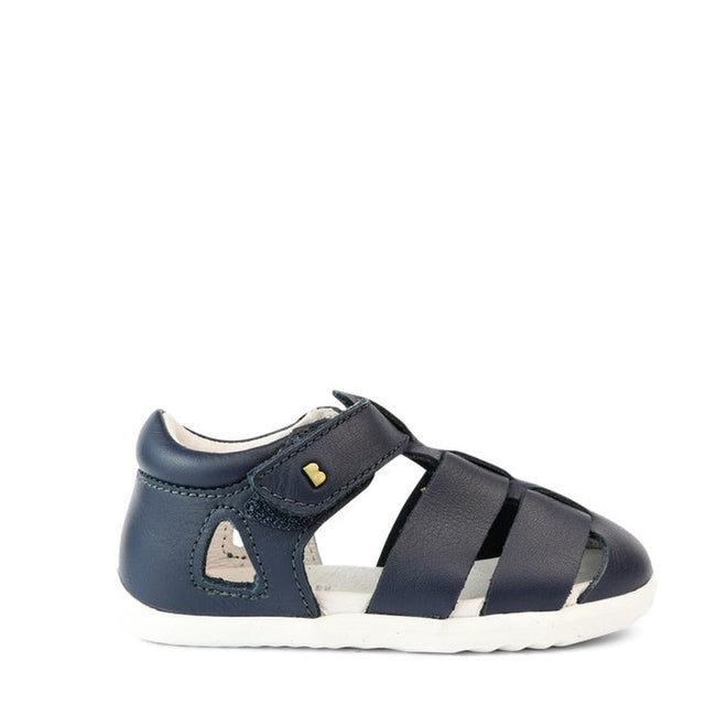 The Bobux Step Up US Tidal Navy Closed Toe Sandal 732503 is a navy toddler sandal with closed toe and heel, open sides, white sole, velcro strap, and a gold heart detail—ideal as first walker shoes., 9420068502574, 9420068502581, 9420068502598, 9420068502604