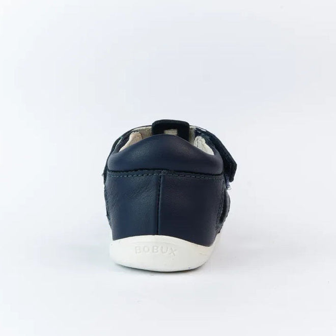The Bobux Step Up US Tidal Navy Closed Toe Sandal 732503 is a navy blue first walker shoe shown from the back, with smooth leather, a white sole embossed with BOBUX, a small heel loop, and a plain white background., 9420068502574, 9420068502581, 9420068502598, 9420068502604