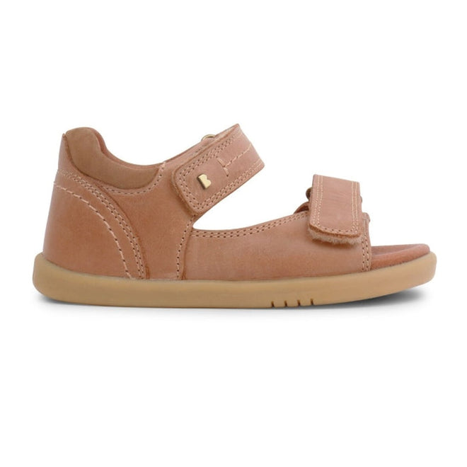 The Bobux IWalk Driftwood Sandal Caramel Open Toe 633606A is a children's light brown sandal with two adjustable Velcro straps and a flat rubber sole, shown in side profile on a white background., 9420062048085, 9420062048078, 9420062048092, 9420062048108, 9420062048115
